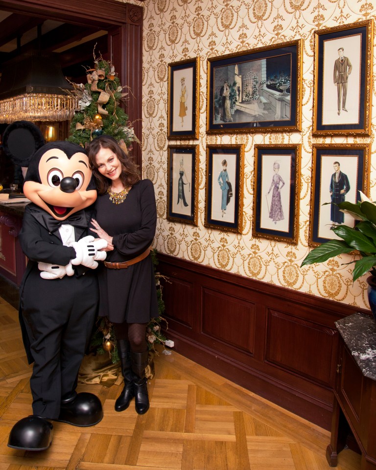 a woman stands next to mickey mouse in a room with pictures on the wall