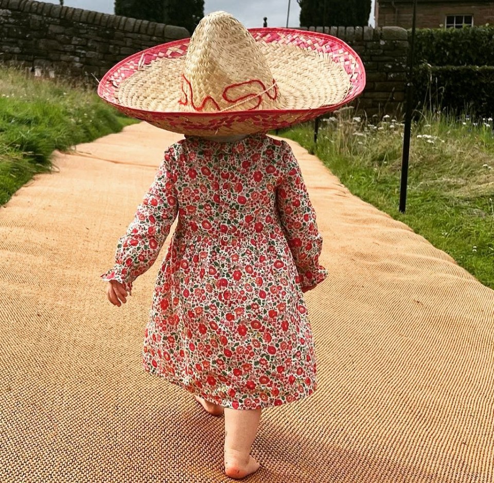 a little girl wearing a sombrero walking down a path