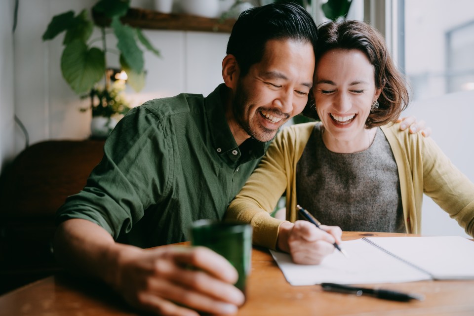 a man and a woman sit at a table laughing