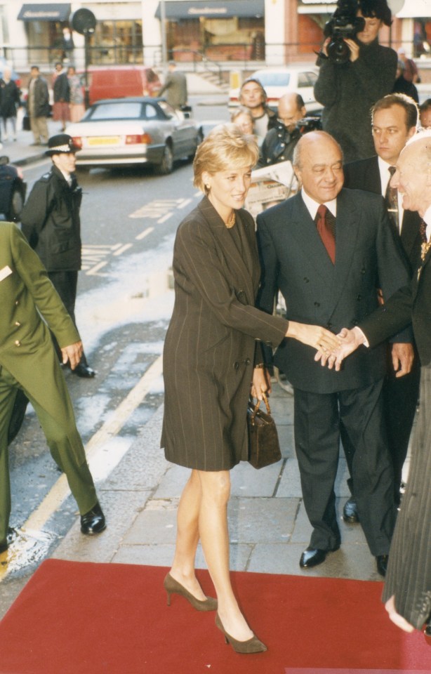 a woman shakes hands with a man on a red carpet