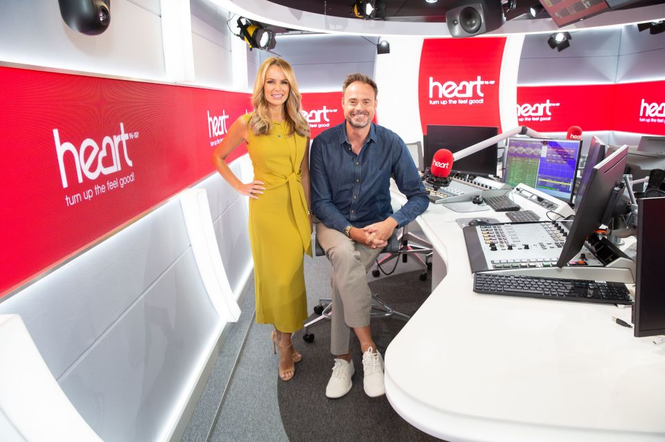 a man and a woman are standing in front of a heart radio station