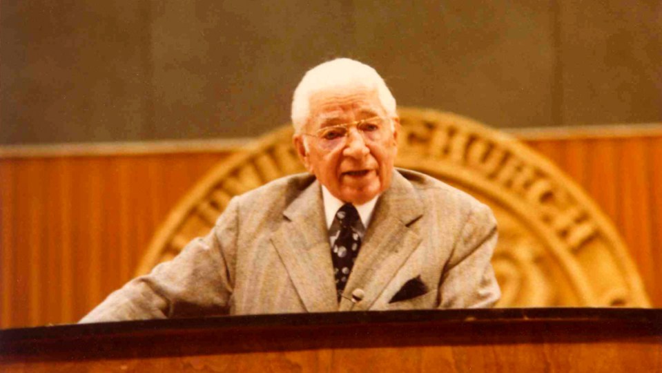 a man stands at a podium with the word church behind him