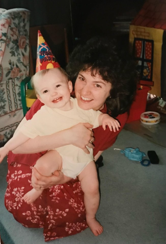 a woman holding a baby wearing a birthday hat