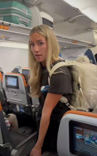 a woman with a backpack is standing on an airplane .