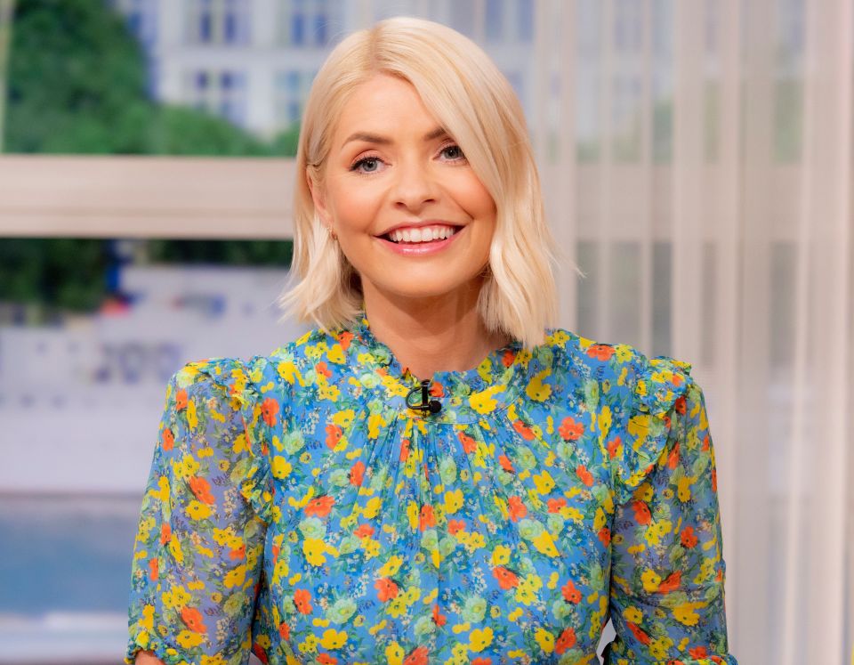 a woman in a blue and yellow floral dress smiles for the camera