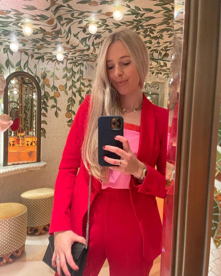 a woman in a red suit takes a selfie in front of a mirror