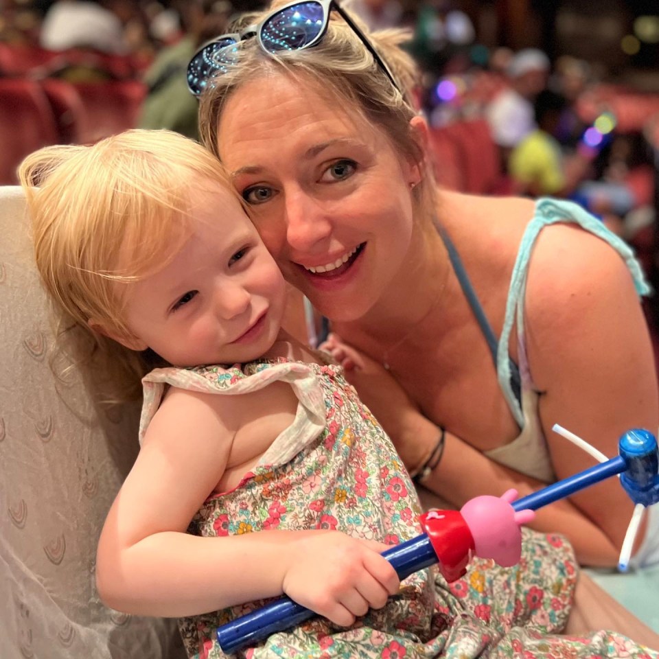 a woman is holding a little girl who is wearing sunglasses