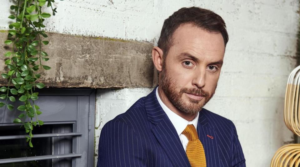 a man in a suit and tie is leaning against a wall