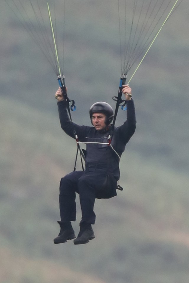 a man wearing a helmet is flying a parachute