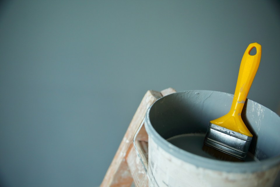 a paint bucket with a yellow paint brush in it