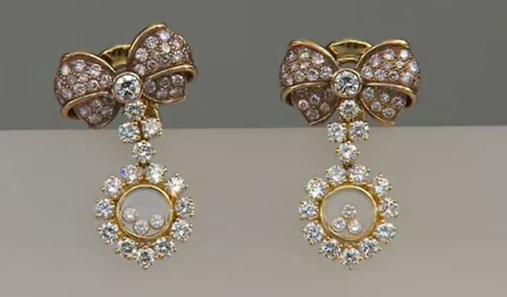 a pair of earrings with a bow and diamonds on a white surface .