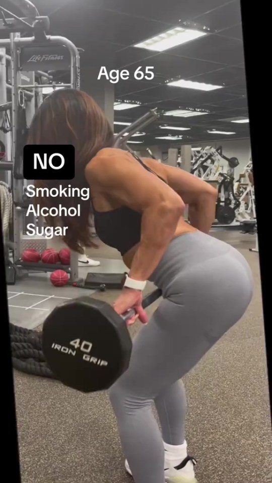 a woman lifting a dumbbell in a gym with a caption that says age 65