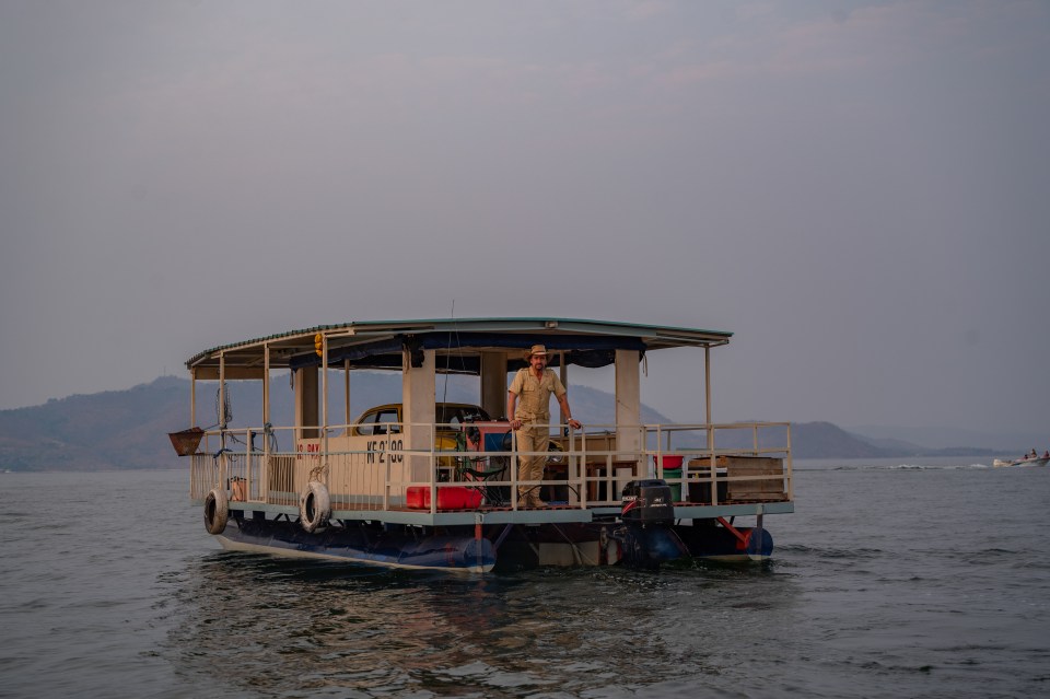 a man stands on the deck of a boat which has a sign on the side that says ' fishing '