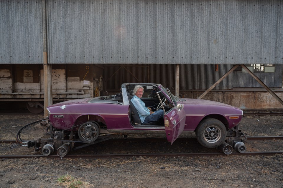 a man sits in a purple car with the door open