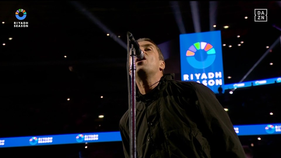 a man singing into a microphone in front of a sign that says riyadh season