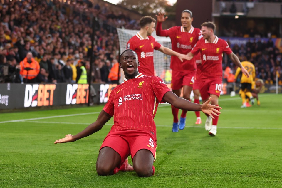 a soccer player wearing a red jersey that says standard chartered on it