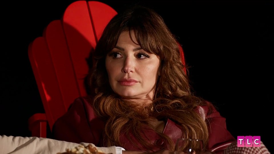 a woman sits in a red chair with tlc written on the bottom