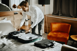 a man is packing a suitcase in a hotel room