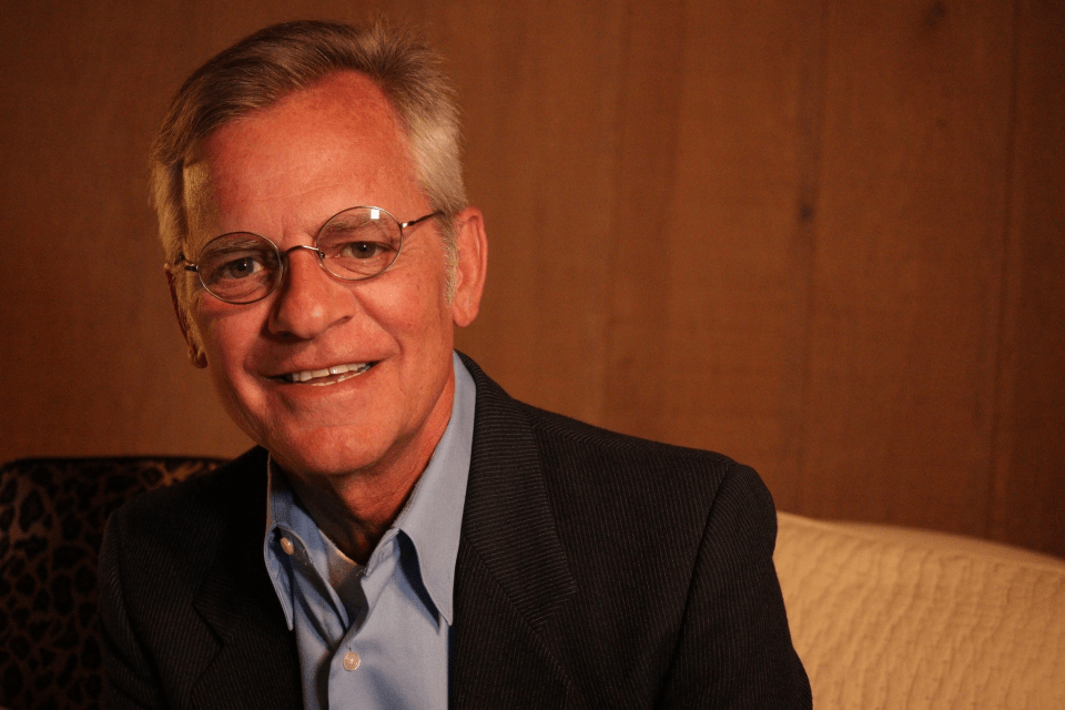 a man wearing glasses and a suit smiles for the camera