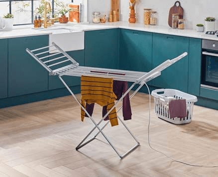 a clothes drying rack is sitting in a kitchen next to a laundry basket .