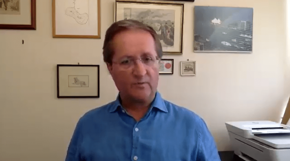 a man in a blue shirt is standing in front of a wall with pictures on it