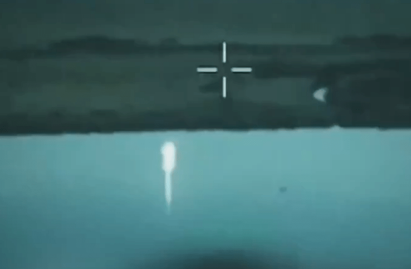 a crosshair on a screen shows a rocket flying over a body of water .