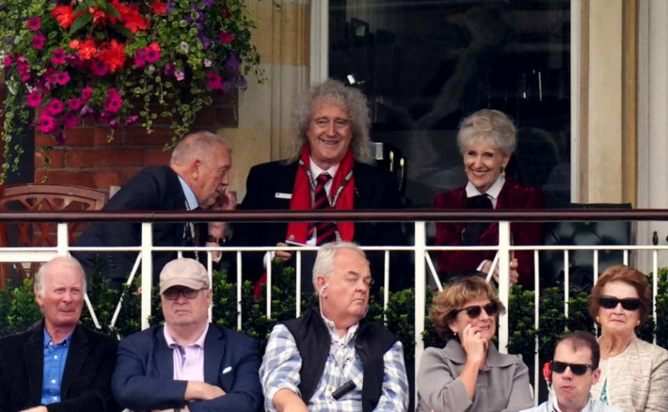 a group of people sitting on a balcony including brian may