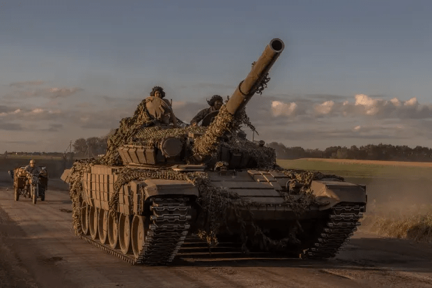 a military tank is driving down a dirt road