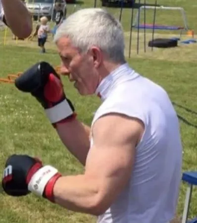 a man wearing boxing gloves is standing in a field .