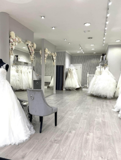 a room with a lot of white dresses on display