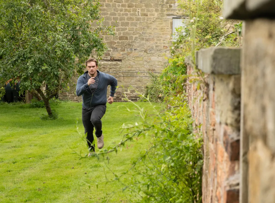 a man wearing headphones is running in a garden