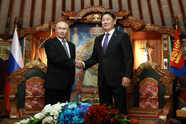 two men shaking hands in front of a painting that says ' mongolia ' on it