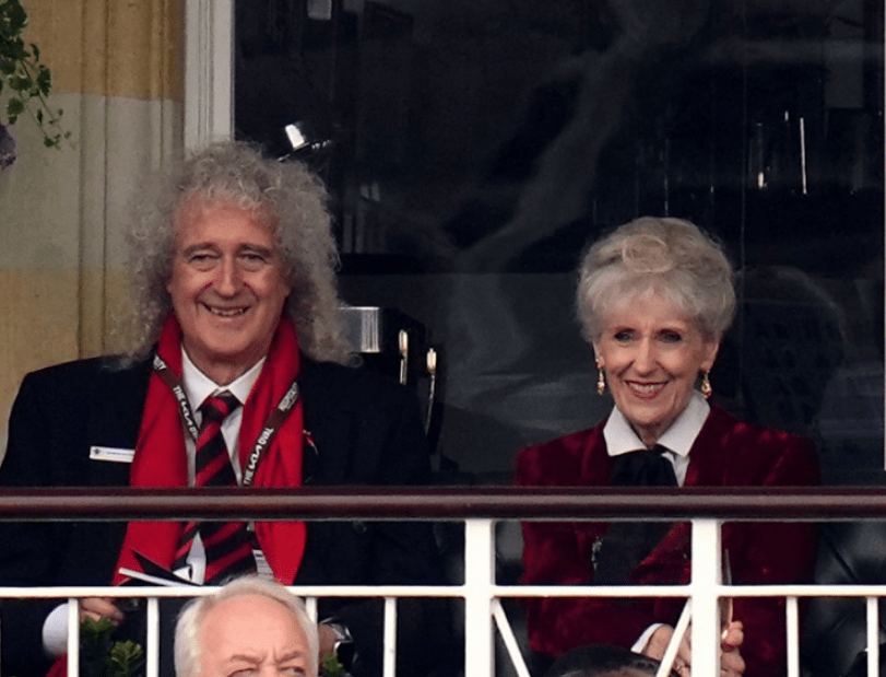 a man and a woman are sitting in front of a window and the man is wearing a scarf that says bbc on it