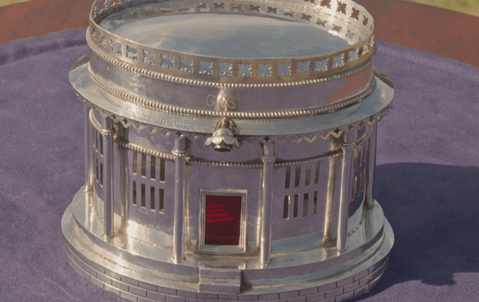 a silver sculpture of a building with a red door