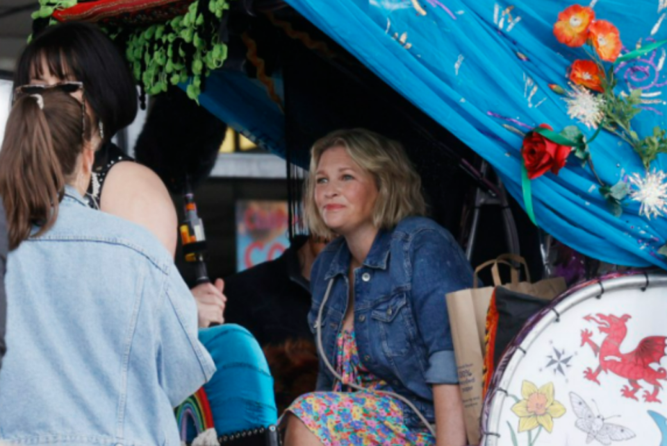 a woman in a denim jacket sits in a tent