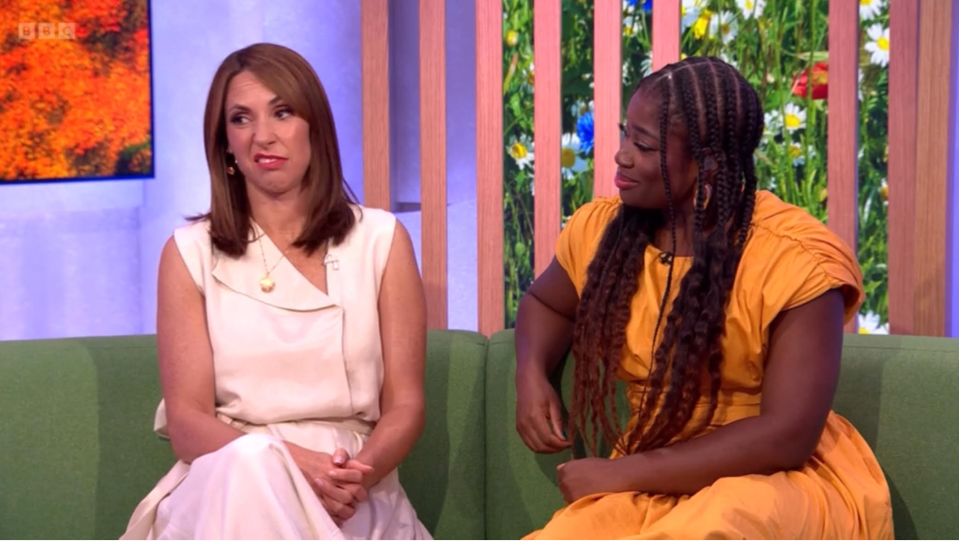 two women are sitting on a green couch and one of them is wearing a yellow dress