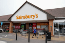 a woman pushes a shopping cart in front of sainsbury 's