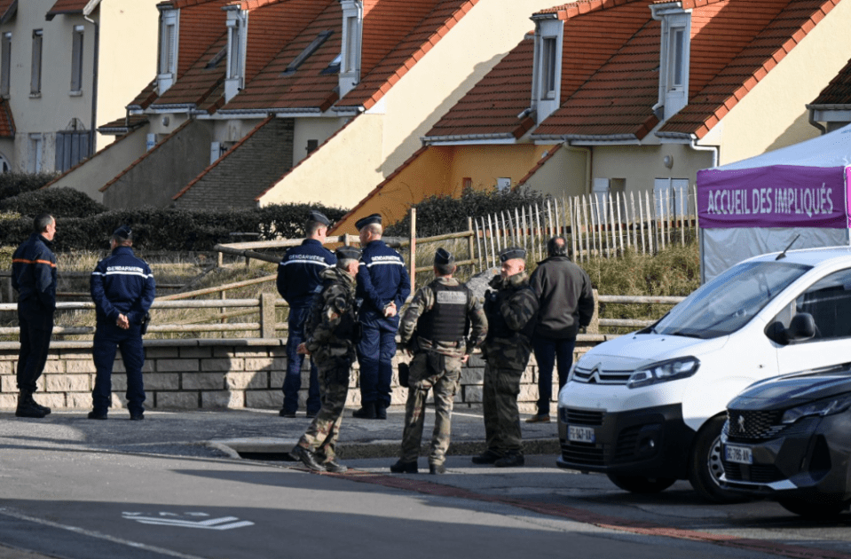 French gendarme and a member of the Civil Defence stand in front of a tent that receives migrants