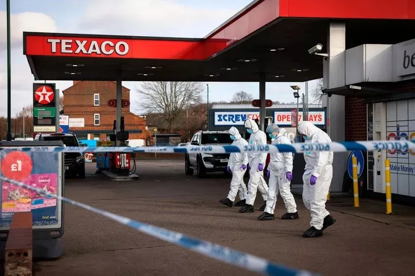 a group of people in white suits are standing outside of a texaco gas station