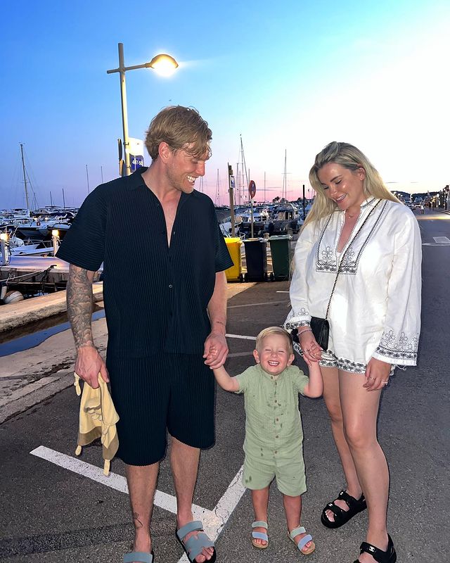 a man and woman holding a child 's hand in a parking lot