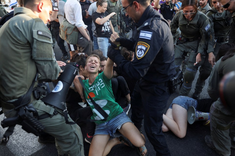 Cops drag a woman away from a demonstration outside Netanyahu's office in Jerusalem