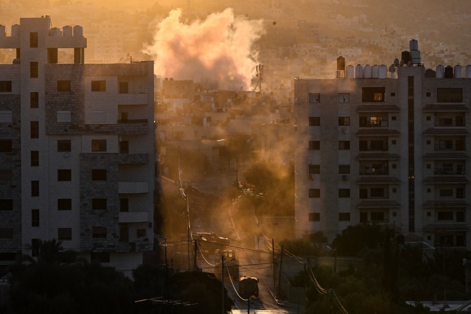 Smoke rises near IDF vehicles in the occupied West Bank, near Jenin refugee camp, as the fighting ramps up in other parts of Palestine