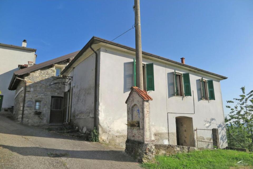 a small white house with green shutters and a small statue in front of it