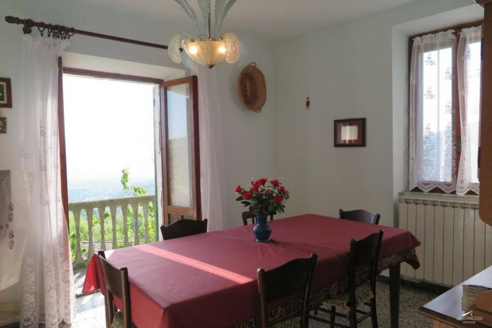 a dining room table with a red table cloth and a vase of flowers on it