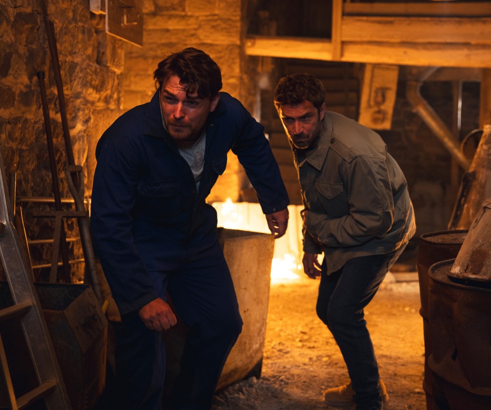 two men standing next to each other in a dark room