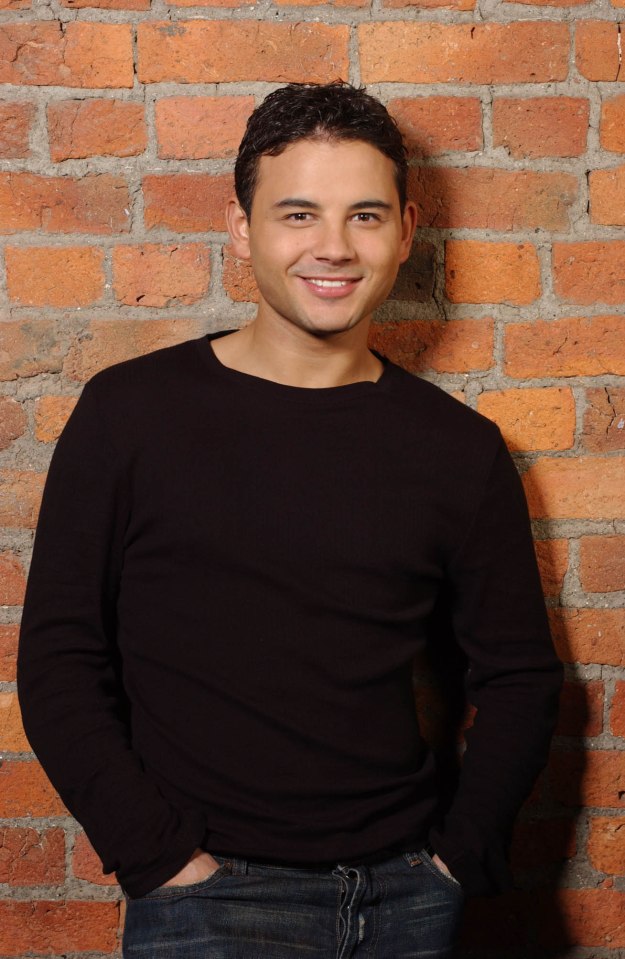 a man in a black shirt stands in front of a brick wall