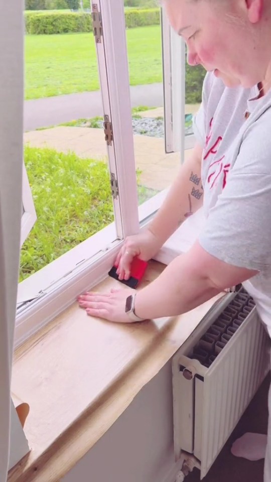 a woman with a tattoo on her arm is using a squeegee on a window sill