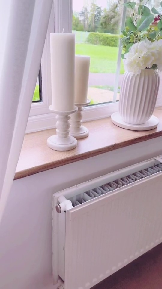 three white candles sit on a window sill next to a radiator