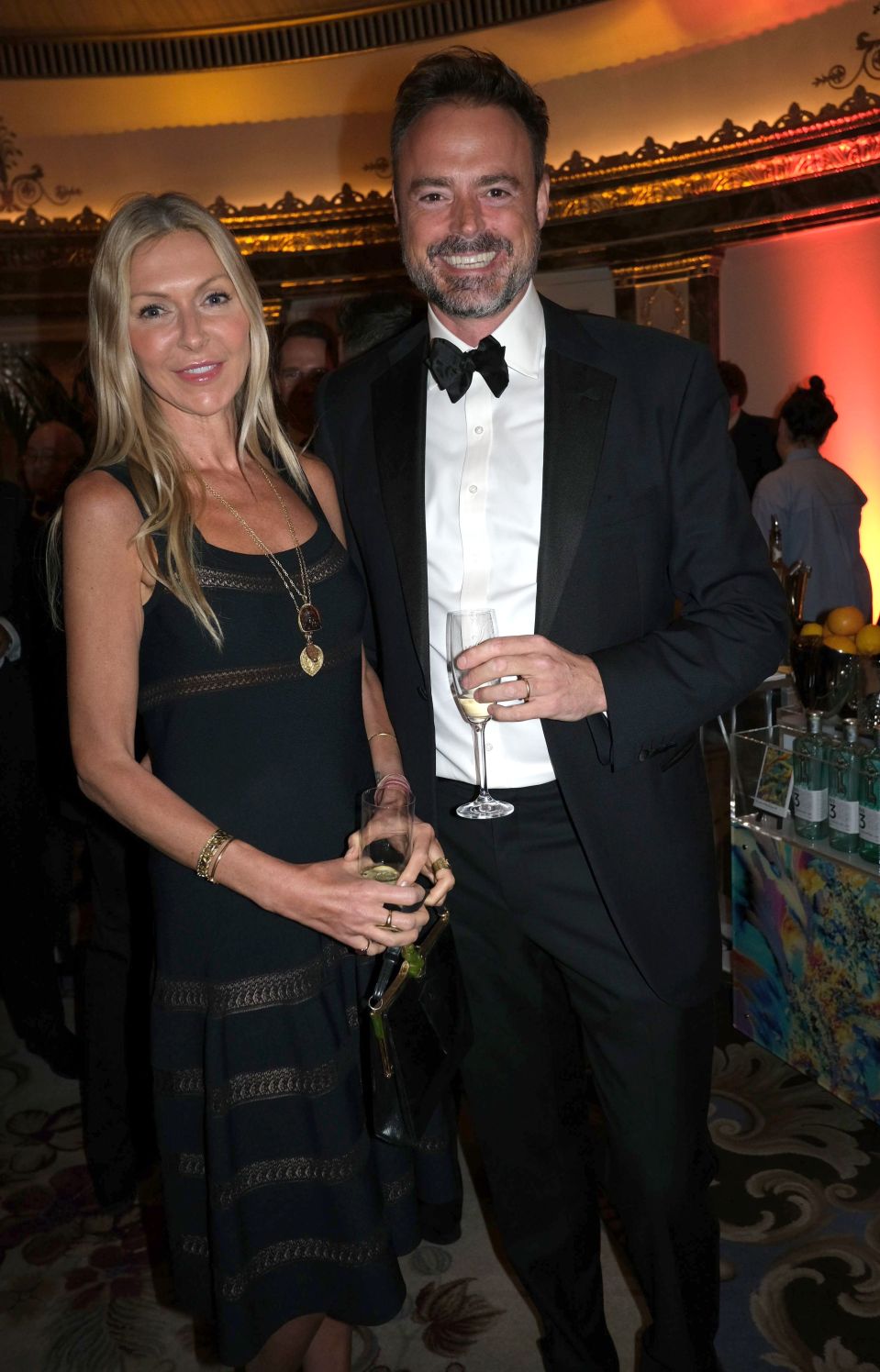 a man in a tuxedo and a woman in a black dress pose for a photo