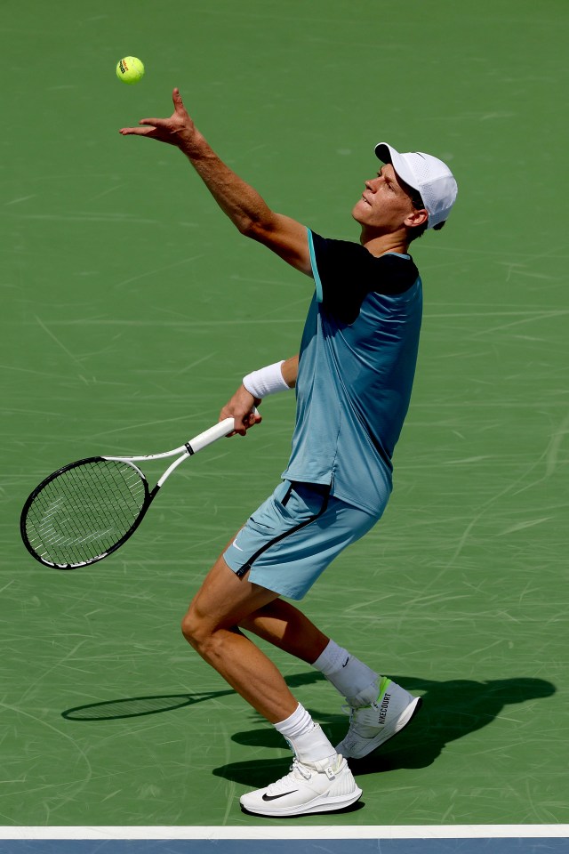 a tennis player in a blue shirt is serving the ball